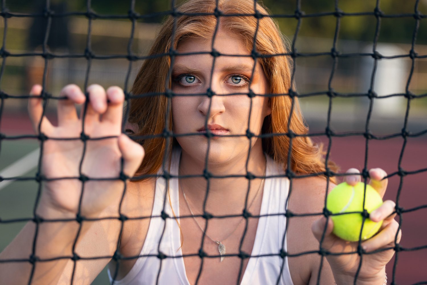 Senior girl tennis player behind net