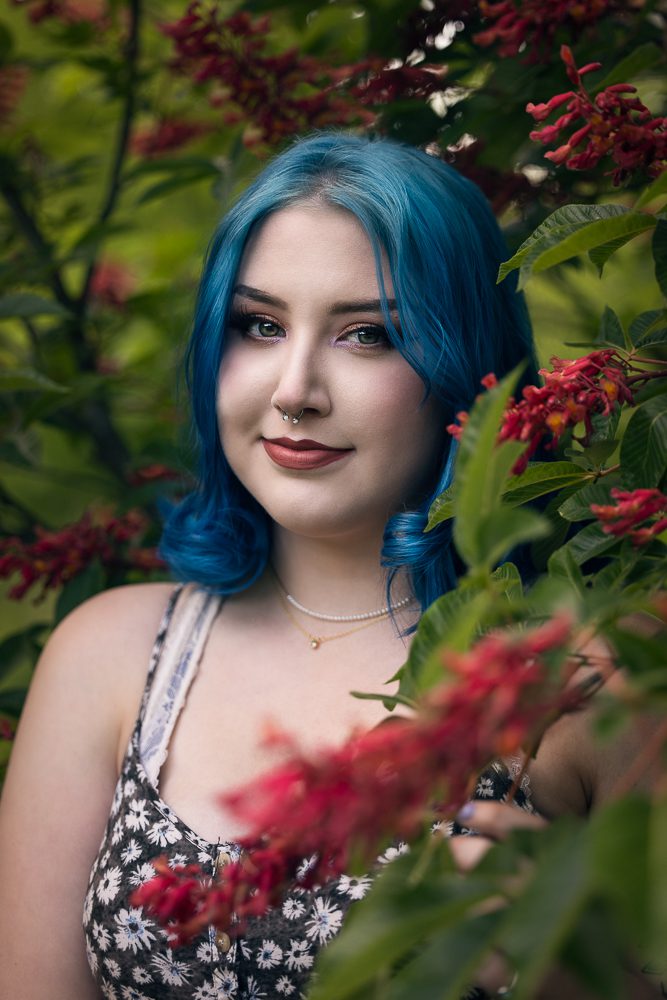 Girl with blue hair among tree foliage