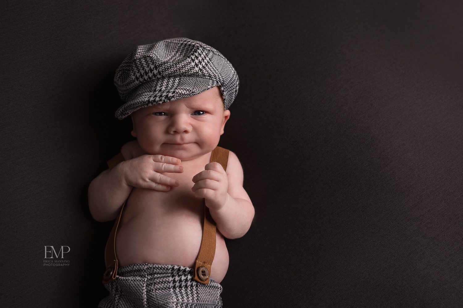 Newborn baby boy in suspenders and cap