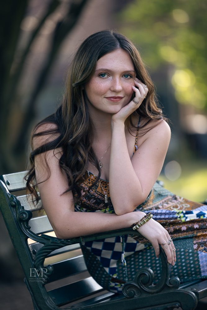 High school senior girl in sundress on a park bench
