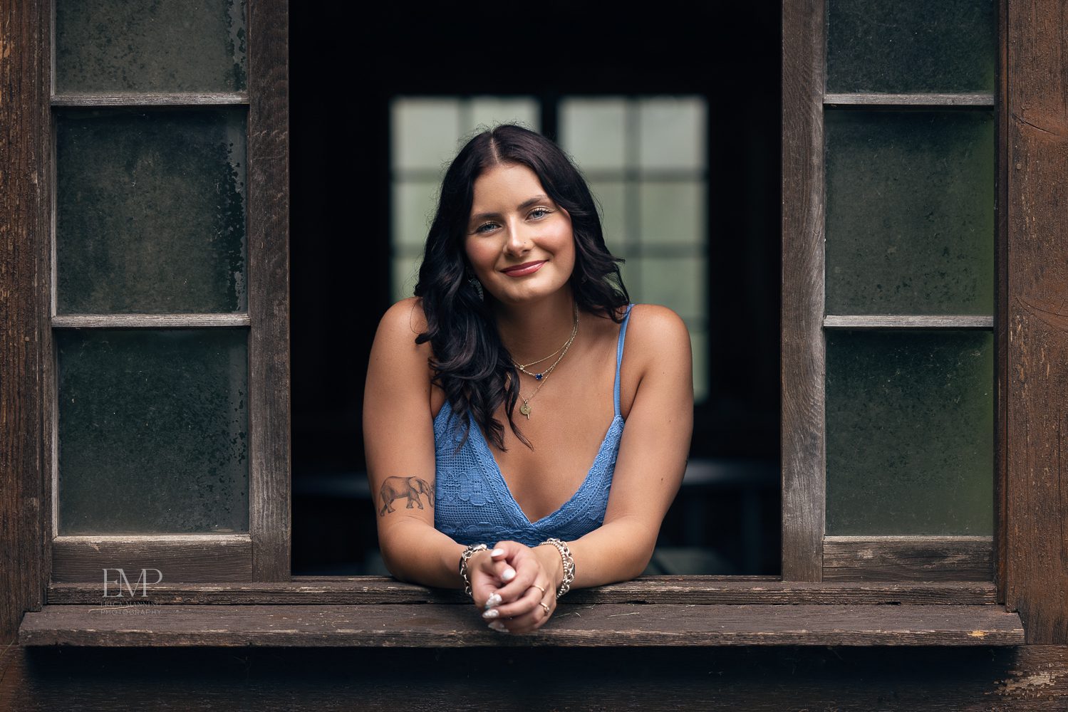 High school senior girl leaning outside of rustic window