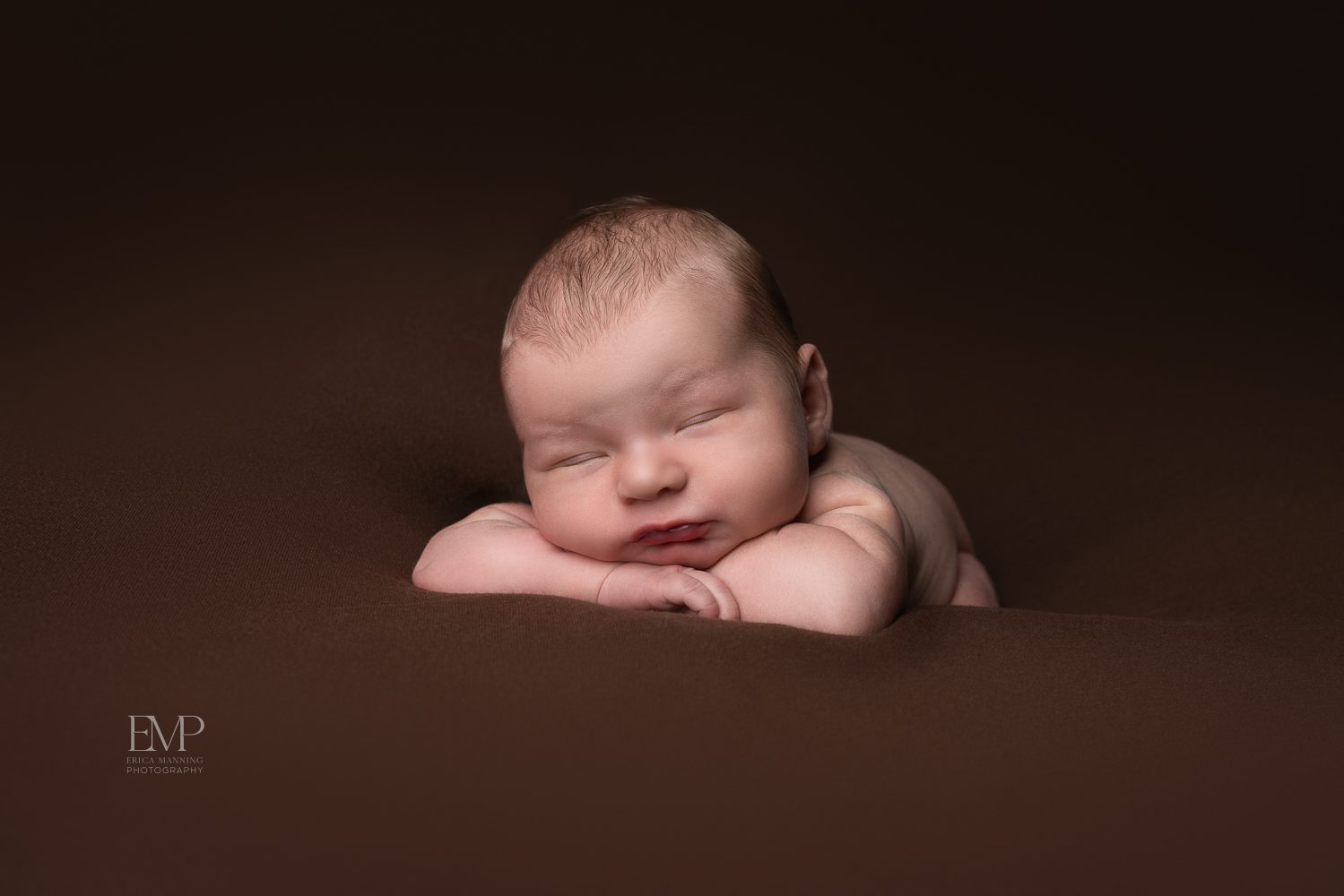 Newborn baby boy on brown blanket studio portrait